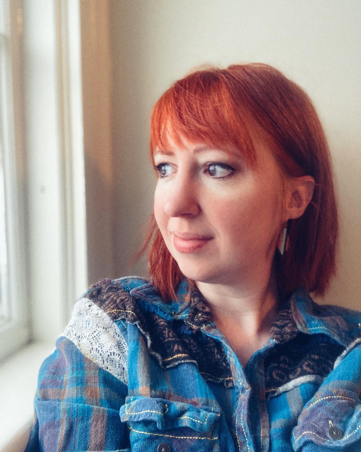 A person with short, red hair and a thoughtful expression.